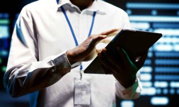Worker using tablet to do assessments of data center rackmounts doing complex calculations, enabling artificial intelligence to process massive datasets for machine learning and AI workloads, close up